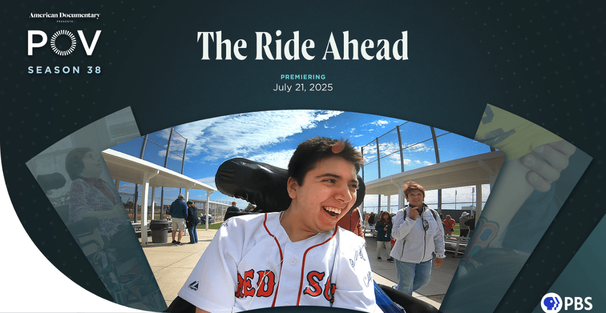 boy wearing a baseball jersey smiling in motorized wheelchair