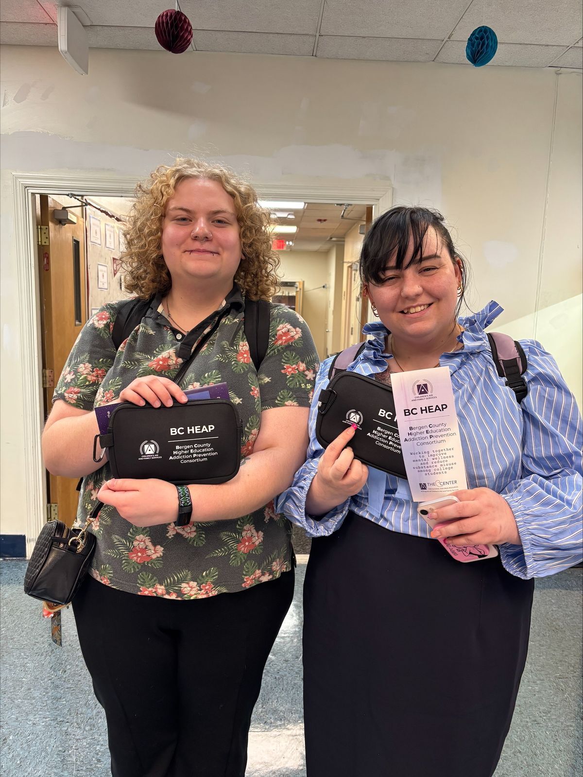 Two students at Eastwick college posing with Narcan kits given away at a tabling event