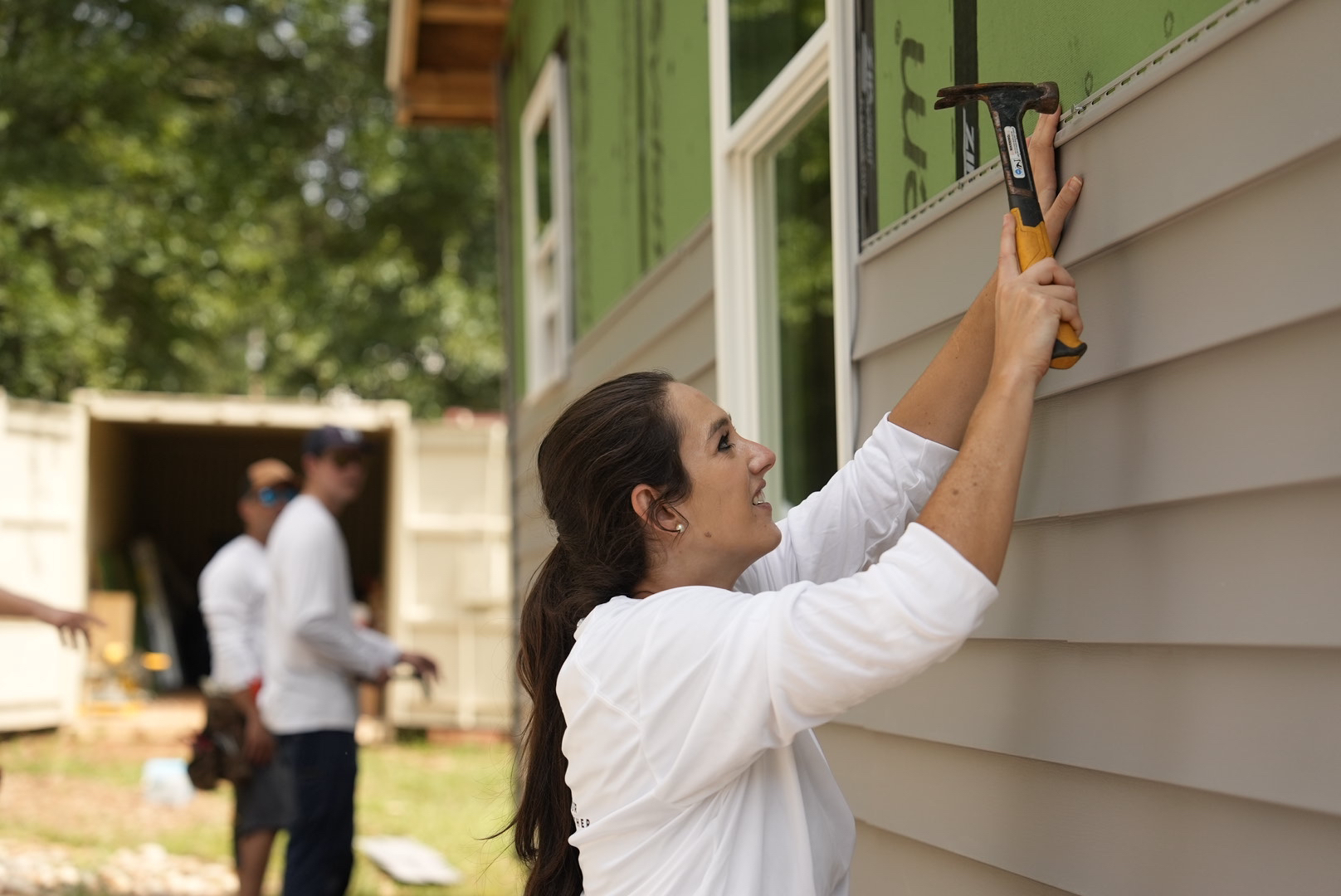 Alair Homes volunteers work to install siding on Ryan St.