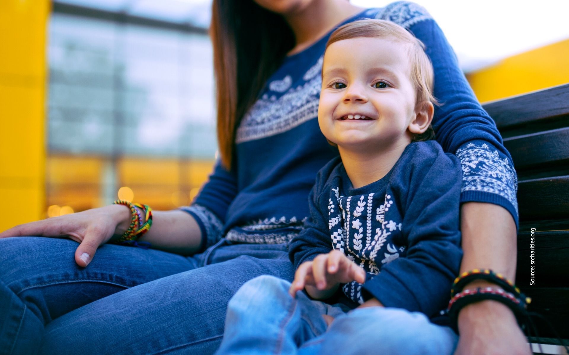 Photo of toddler sitting with mother and smiling