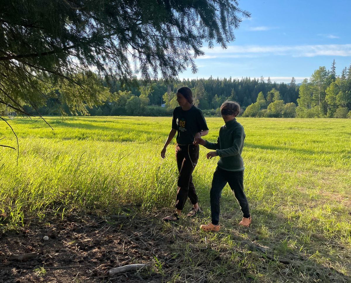 [Image Description: Two Youth Crew Members walking through a field, appearing to be doing a trust exercise.]