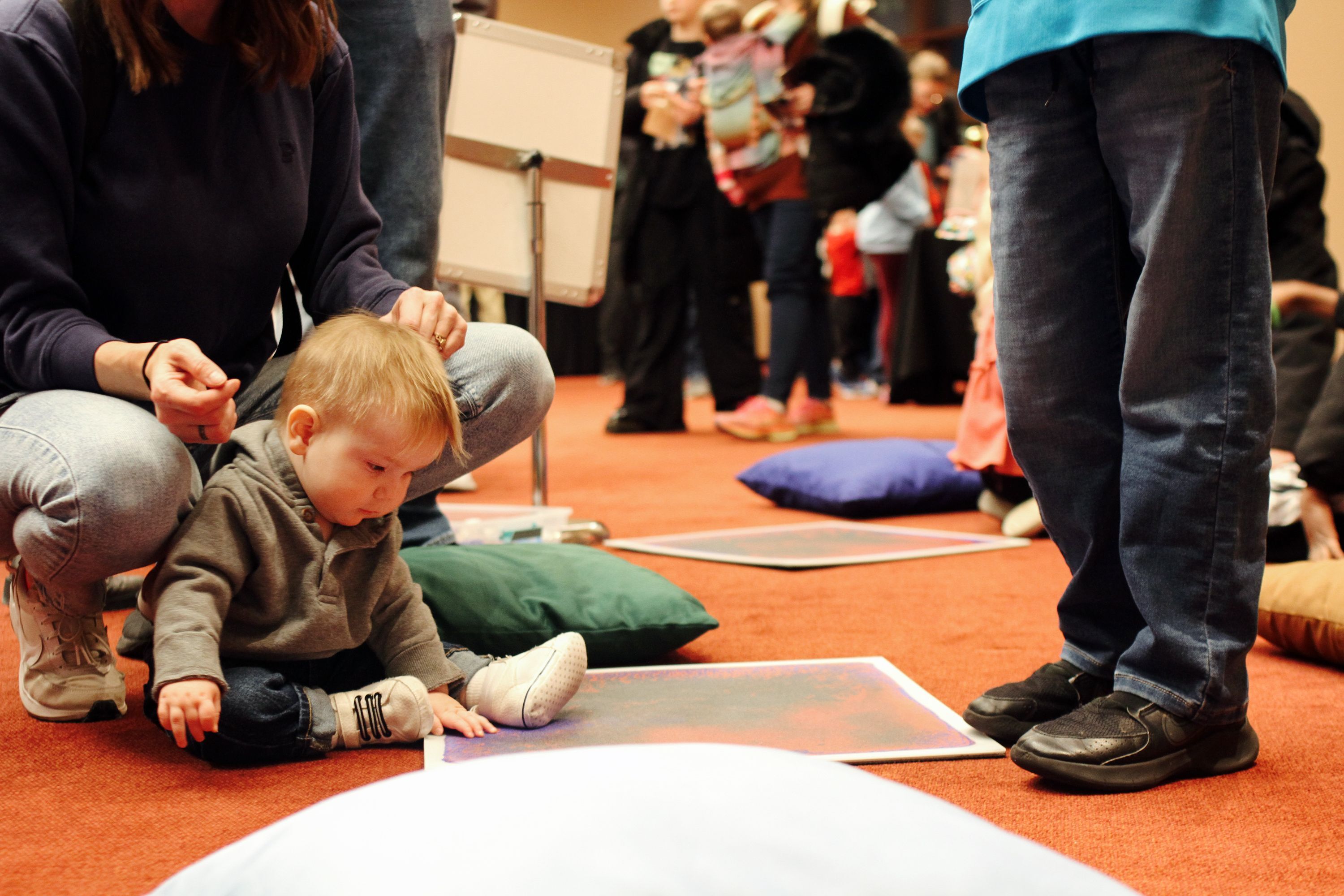 little boy sitting and playing with a sensory tile