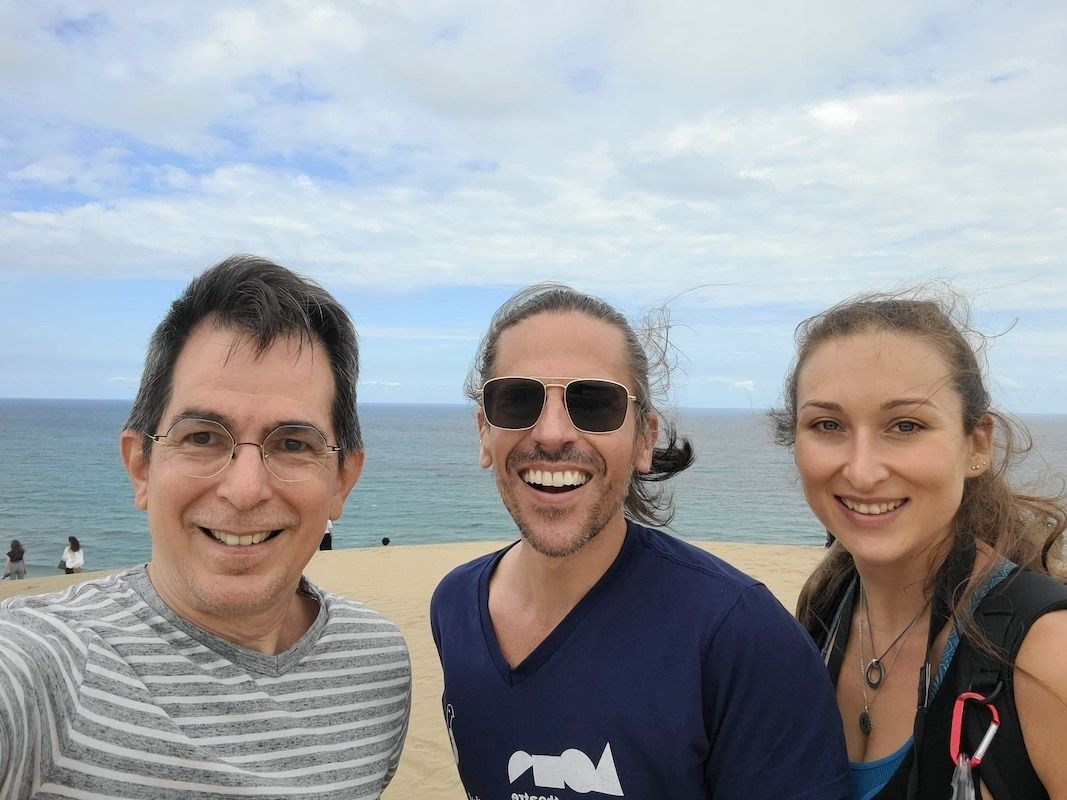 An image of 3 people, ocean and beach.