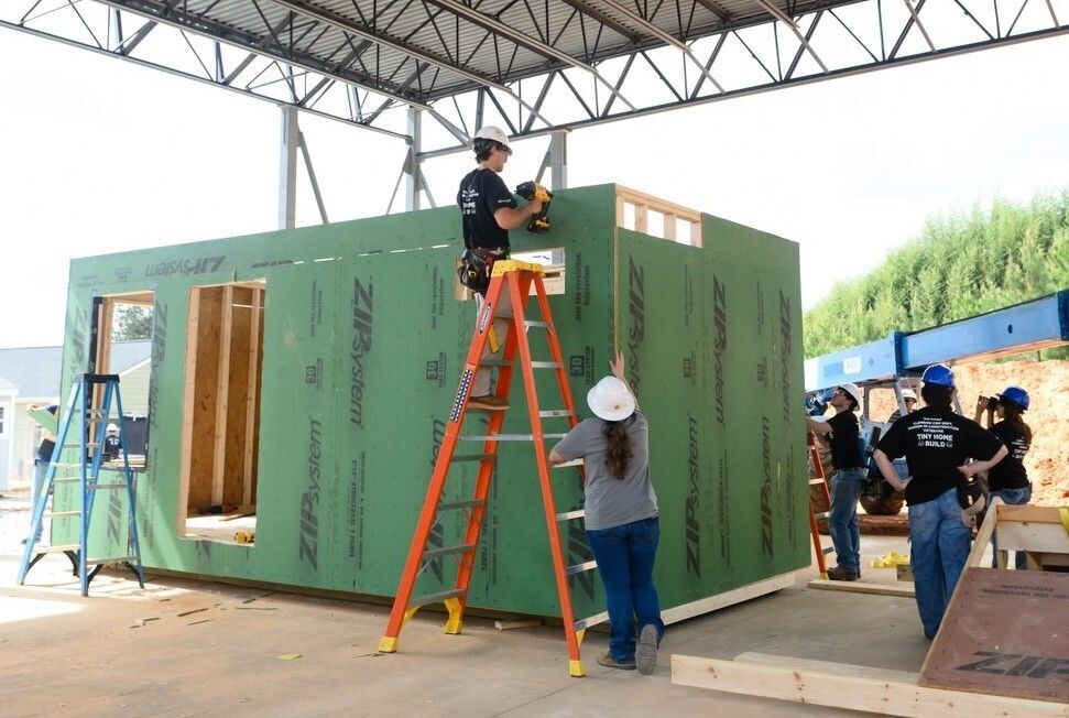 Students and volunteers construct a tiny home under the covered pavilion at Clemson's XL Yard during the second annual Women in Construction Tiny Home Build for Veterans.