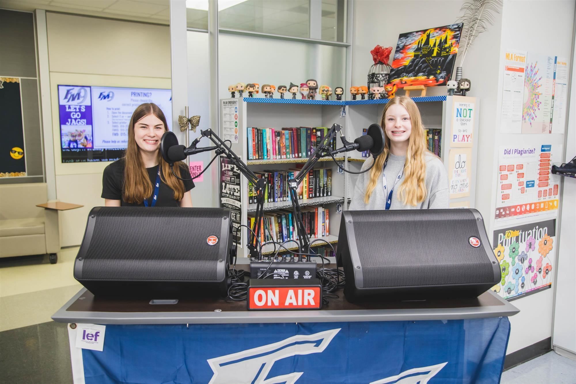 Two students smiling behind the new broadcasting equipment bought from the LEF grant.