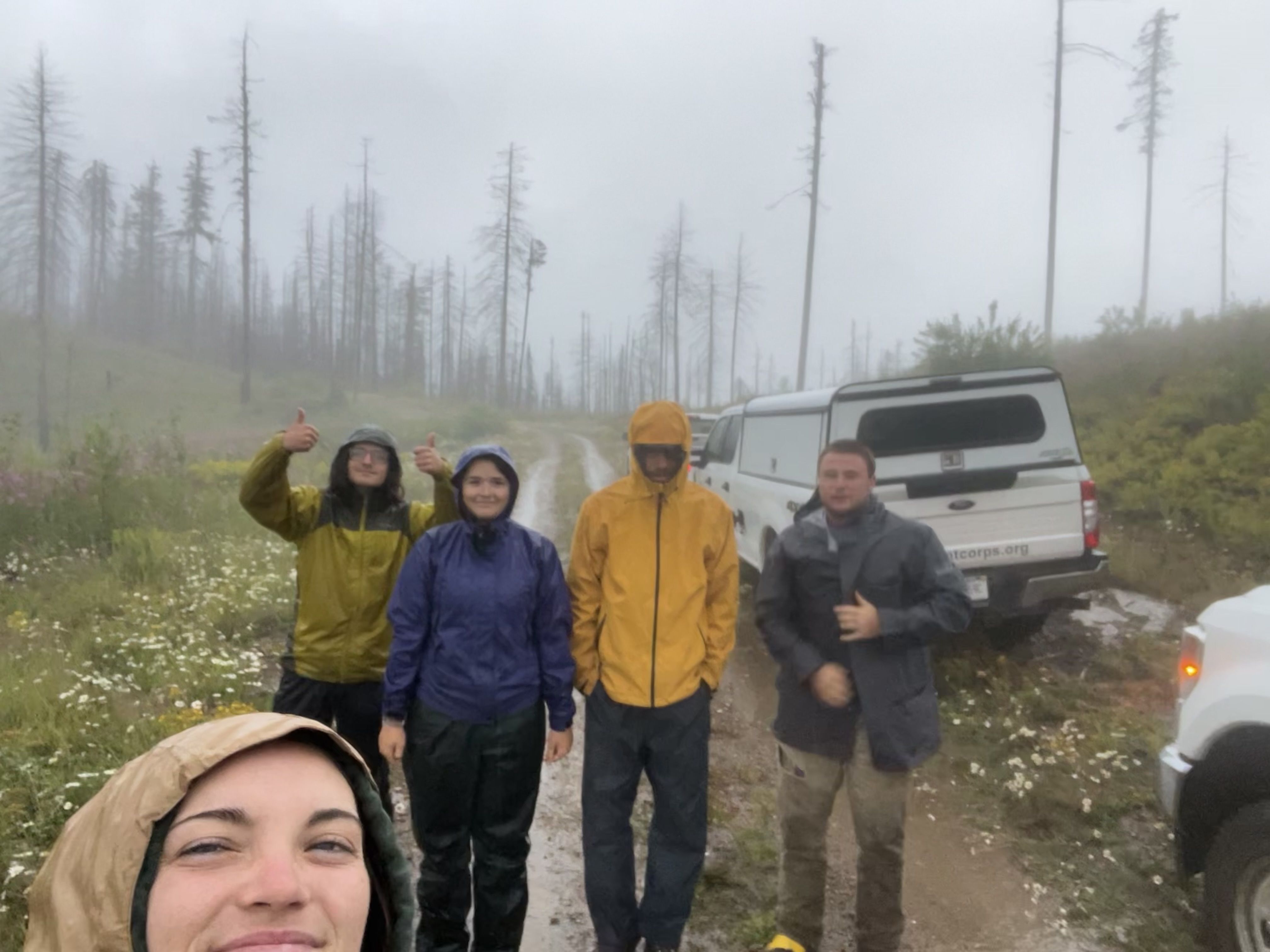 A crew takes a selfie in the rain standing next to an MCC rig.