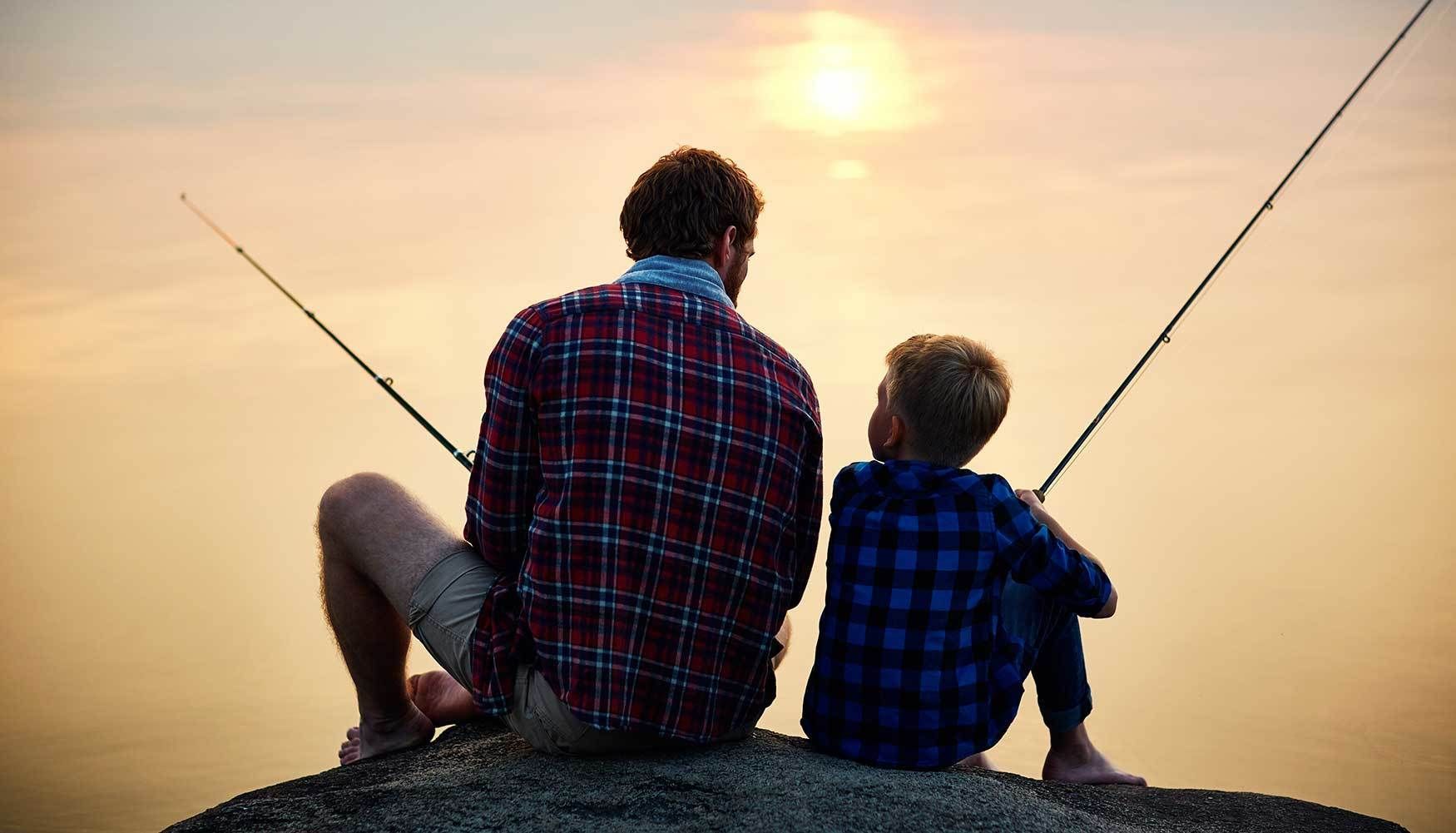 Dad and son fishing during a sunset.