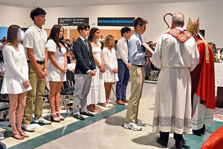 The seven students of St. John Paul II who were to be baptized stand before Bishop Emeritus Gerald Barbarito.
