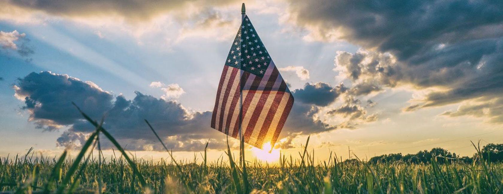 American flag with sunset in the back.
