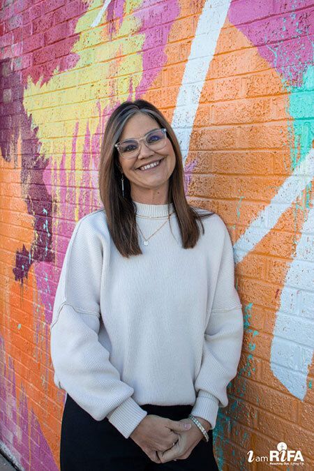 Denice in front of a colorful mural