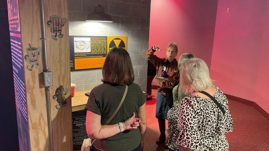 Four women talking in front of a museum exhibit.