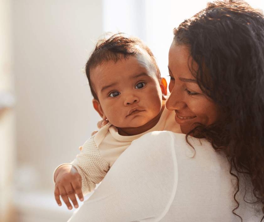 A mother holding and smiling at her baby