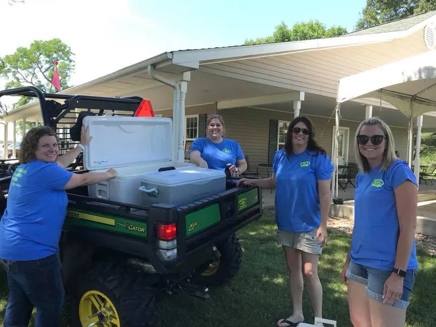 Women in blue shirts delivering drinks to golfers.