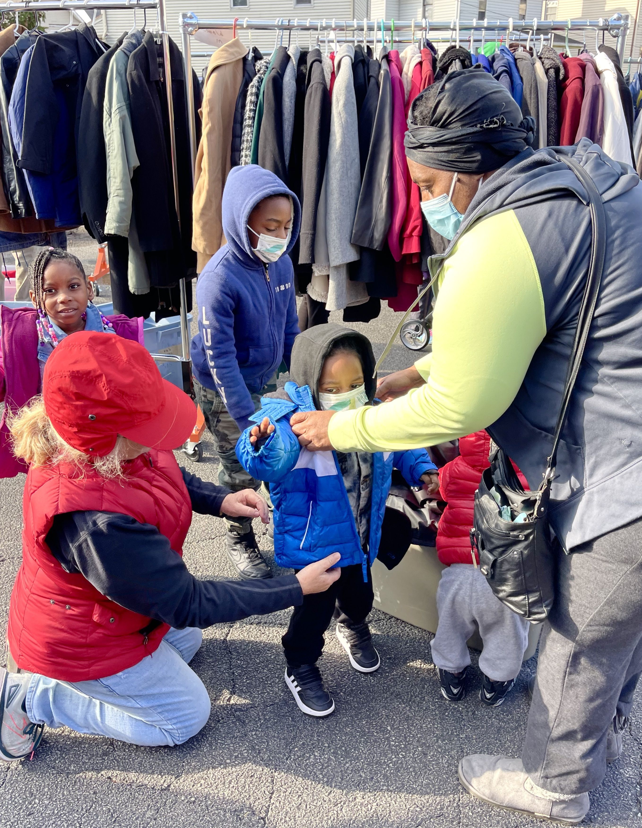 Theresa helps a young man try on a coat.