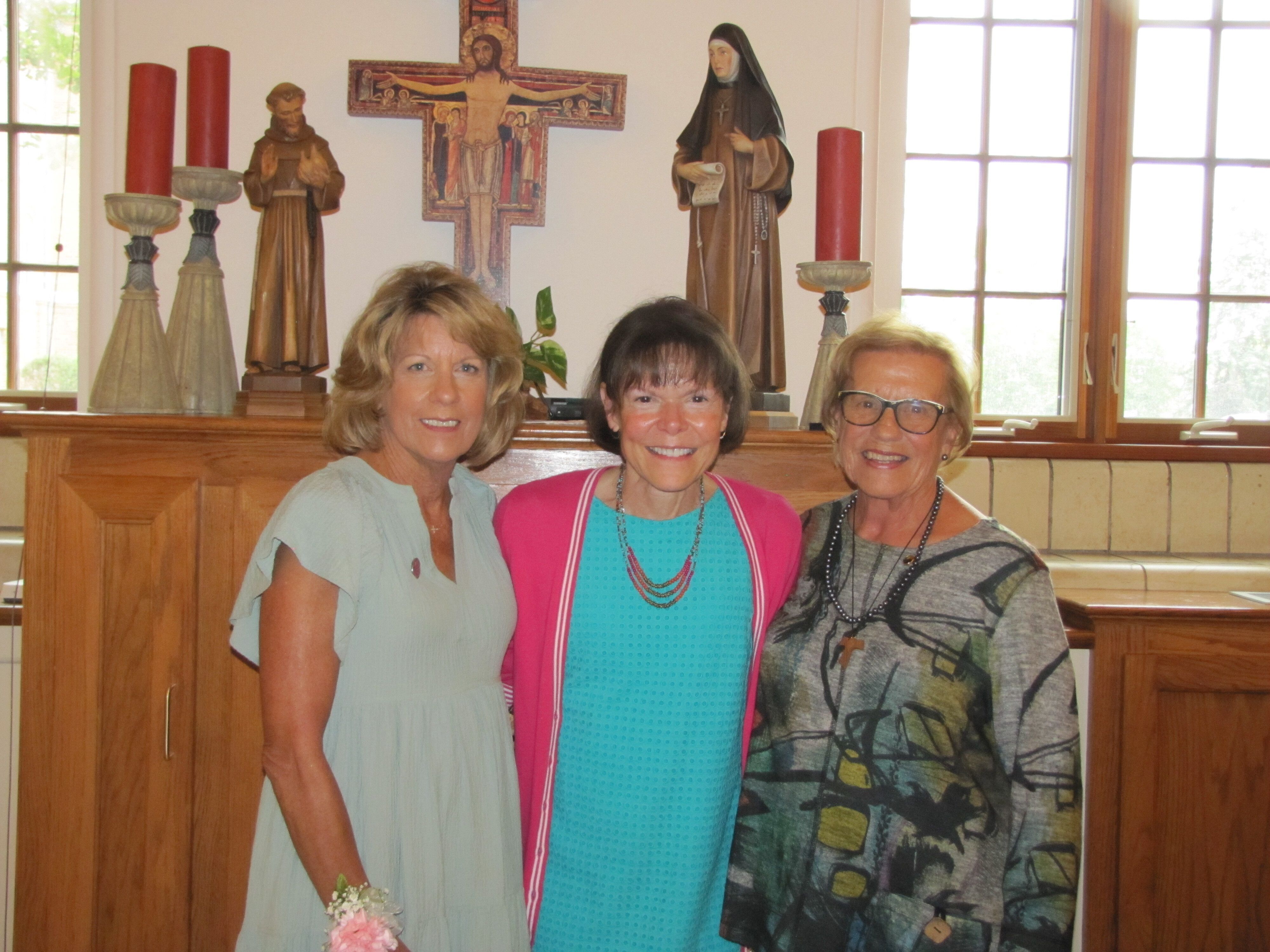 Three women smile together in church.