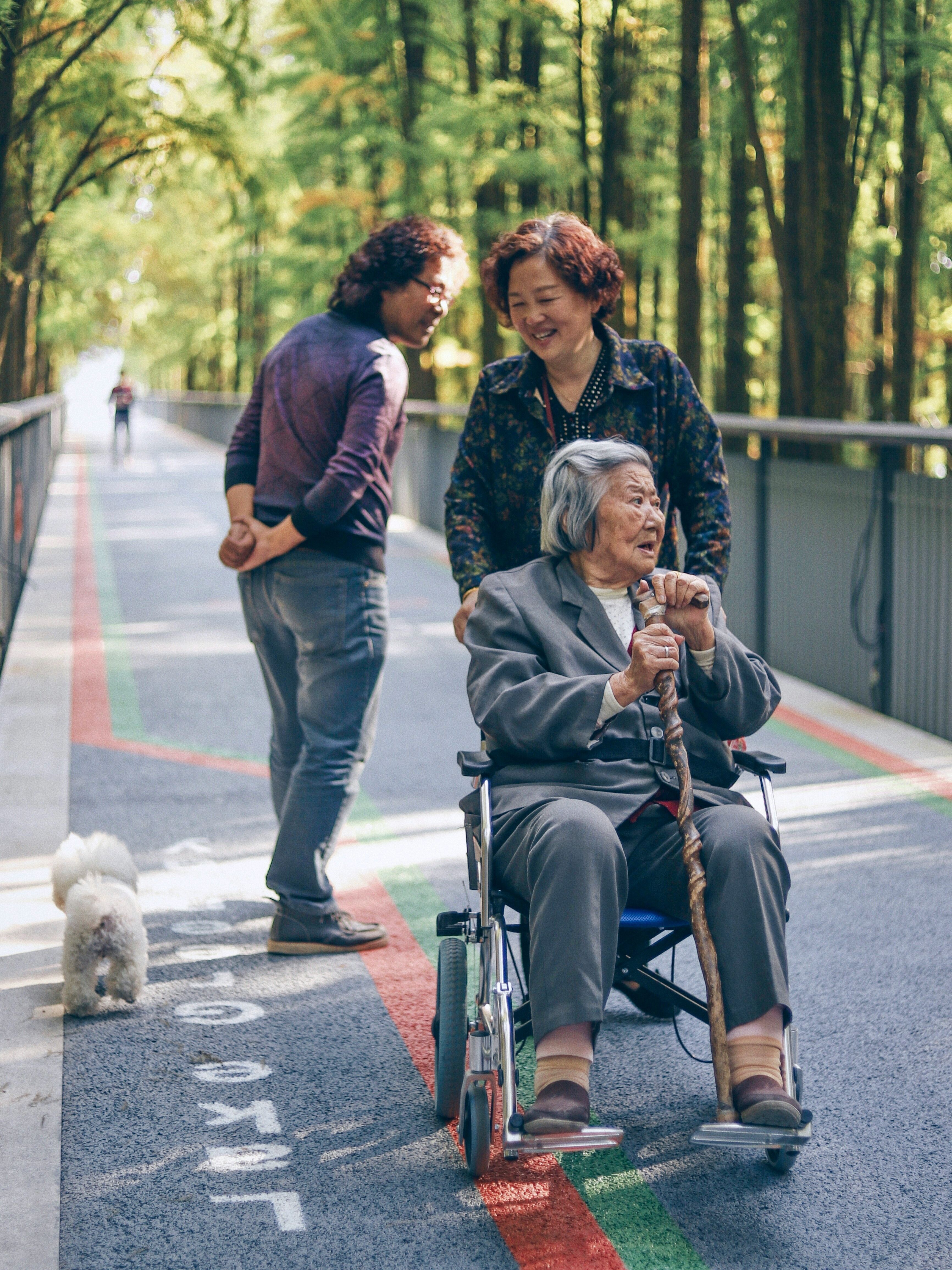 A woman helps an elderly woman in a wheelchair on an outing