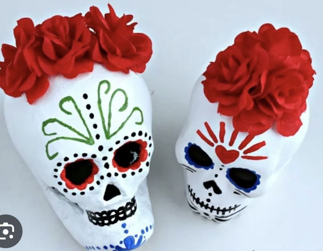 Two painted Day of the Dead skulls decorated with red flowers.