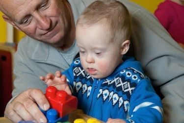 A grandfather playing with his grandson with Down syndrome.