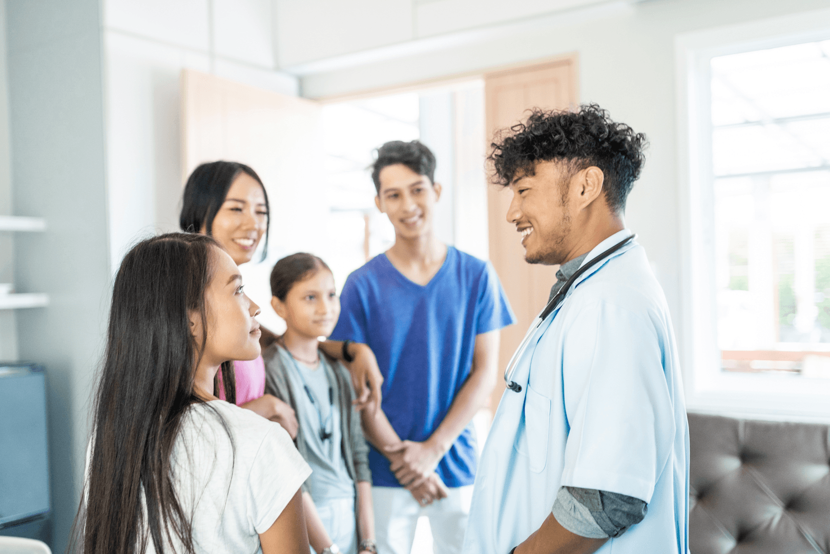 Family of 4 people of Southeast Asian heritage speak with a doctor in a brightly lit room