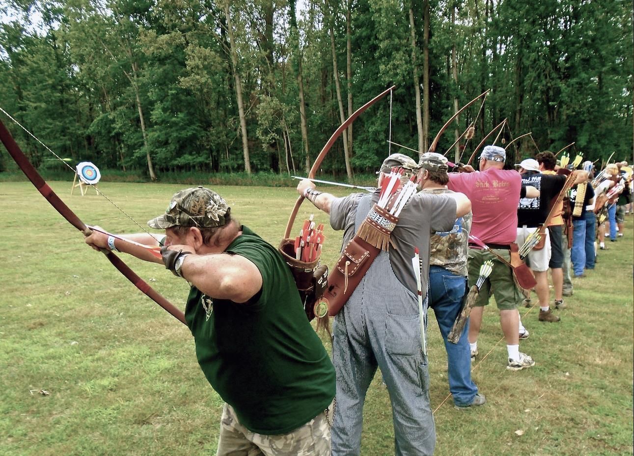 A group of archers shooting their longbows in a line.