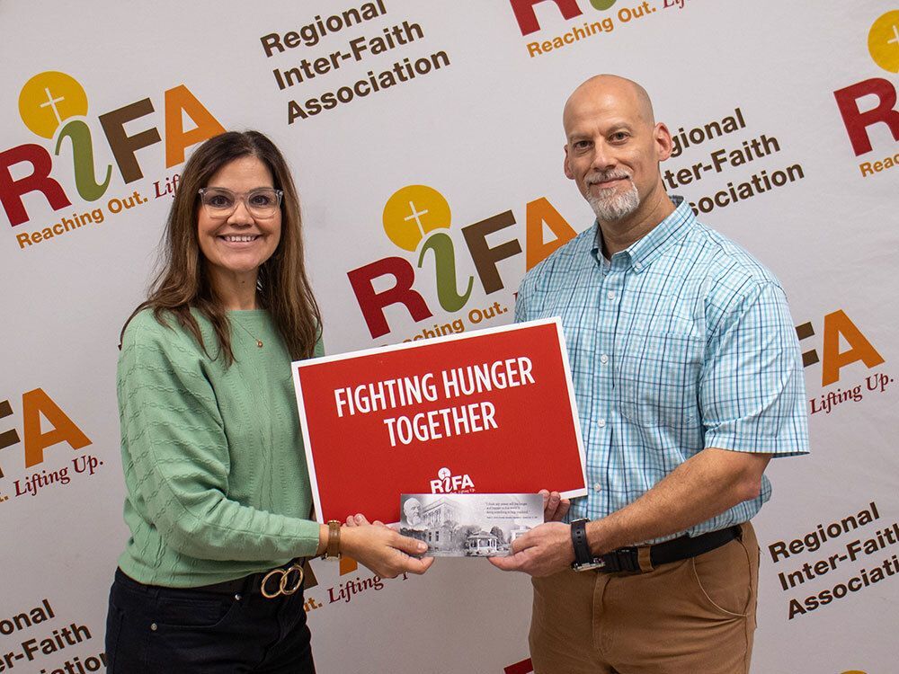 People holding a sign that says "Fighting Hunger Together"