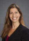 Photo of Dr. Cynthia Levy wearing a red dress, black jacket and smiling at the camera