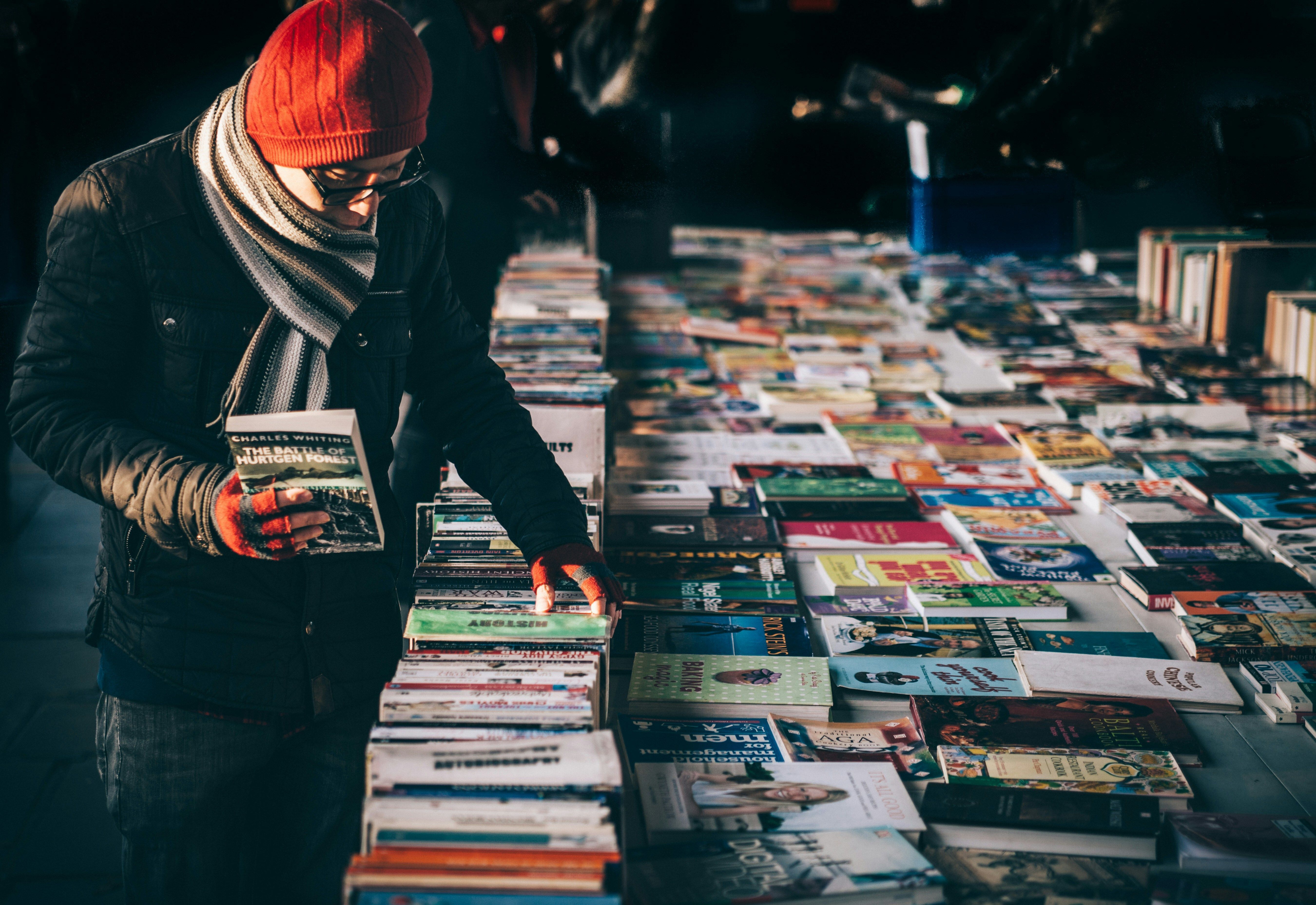 A shopper browsing through a selection of books for sale.