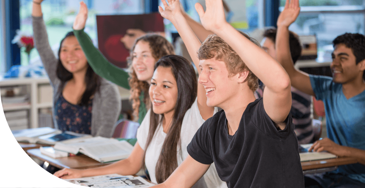 students in a classroom raising their hands