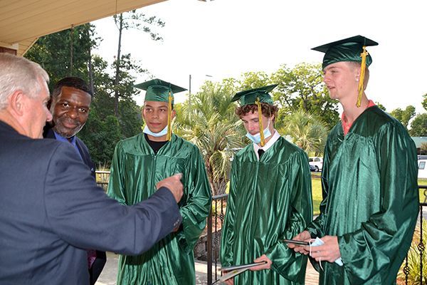 Board Chair Larry Hewett speaks with the summer graduates at Thomas Academy Principal George Ward looks on.