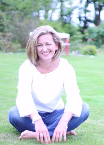 Photo of Carol Brill smiling while sitting on grass