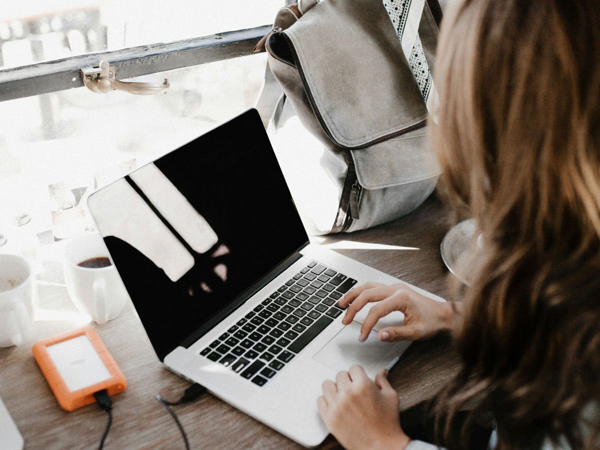 employee working at a computer with a backpack in the background