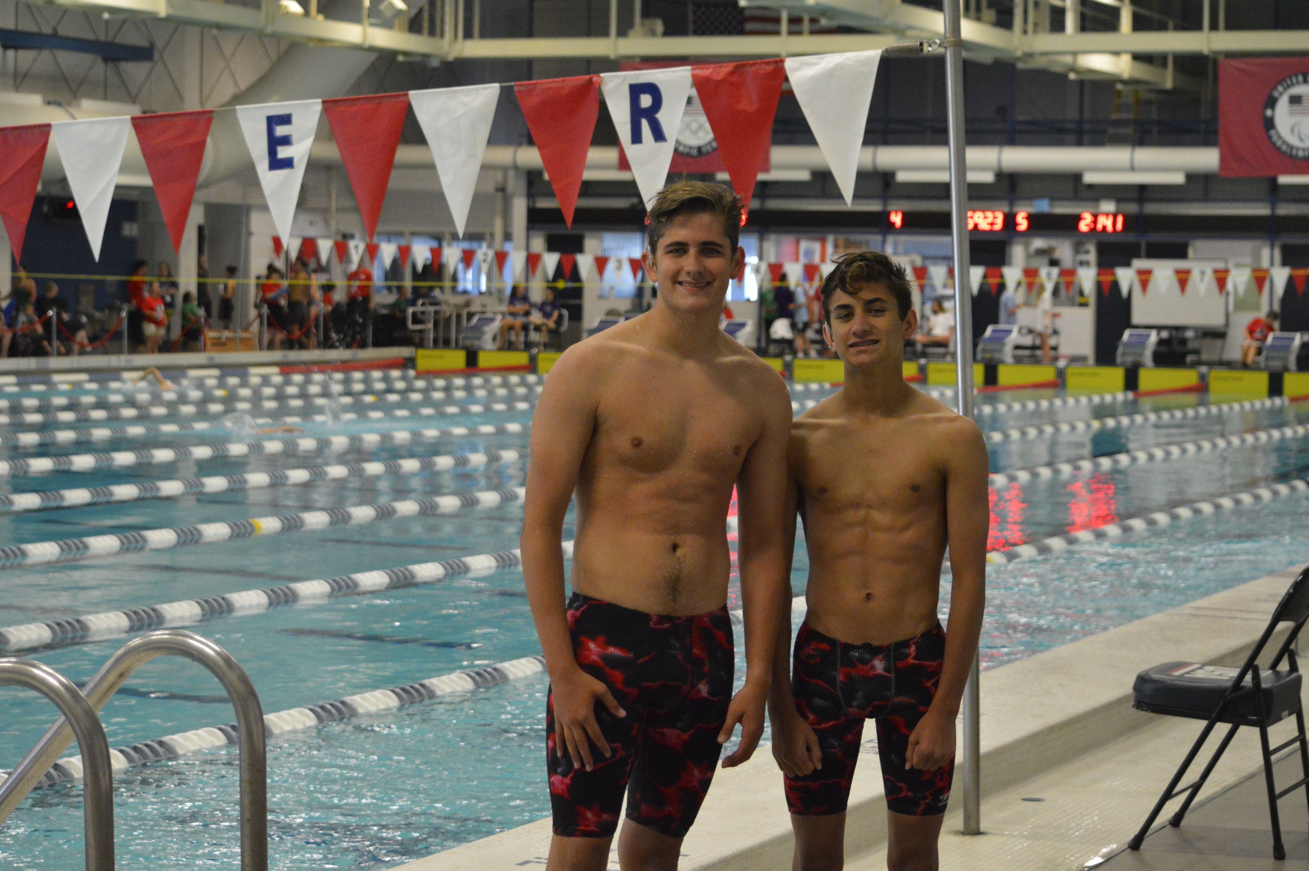 A picture of two teen boys, Ethan and Gavin, wearing red and black swim shorts, standing in front of a pool. 