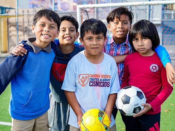 Kids holding a soccer ball as they pose during a game.