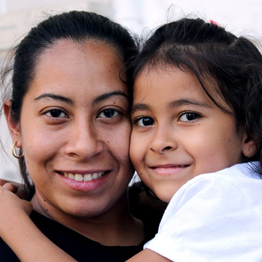 Up close photo of Mom smiling holding her daughter.