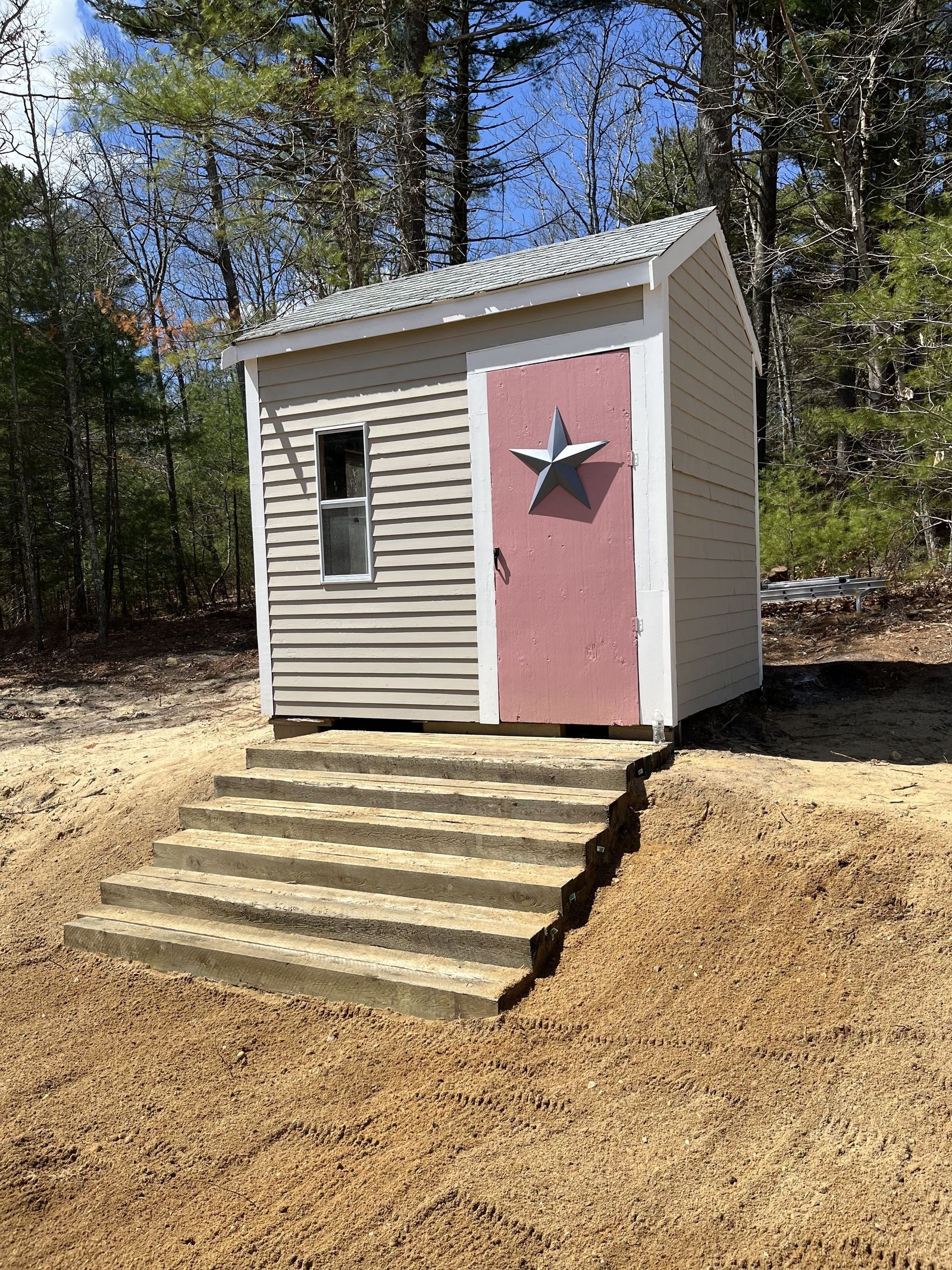 A photo showing a small shed with fresh paint and new steps leading to it