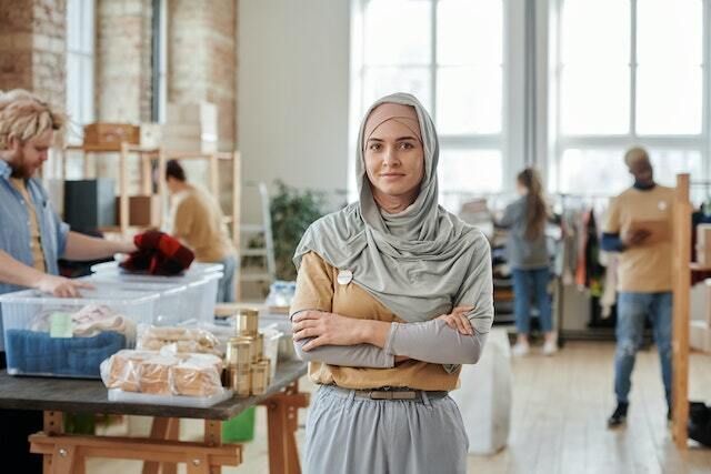 Woman wearing a head scarf smiling while standing in a workshop