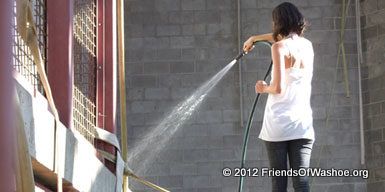 A caregiver washes the cement platform in the outdoor area.