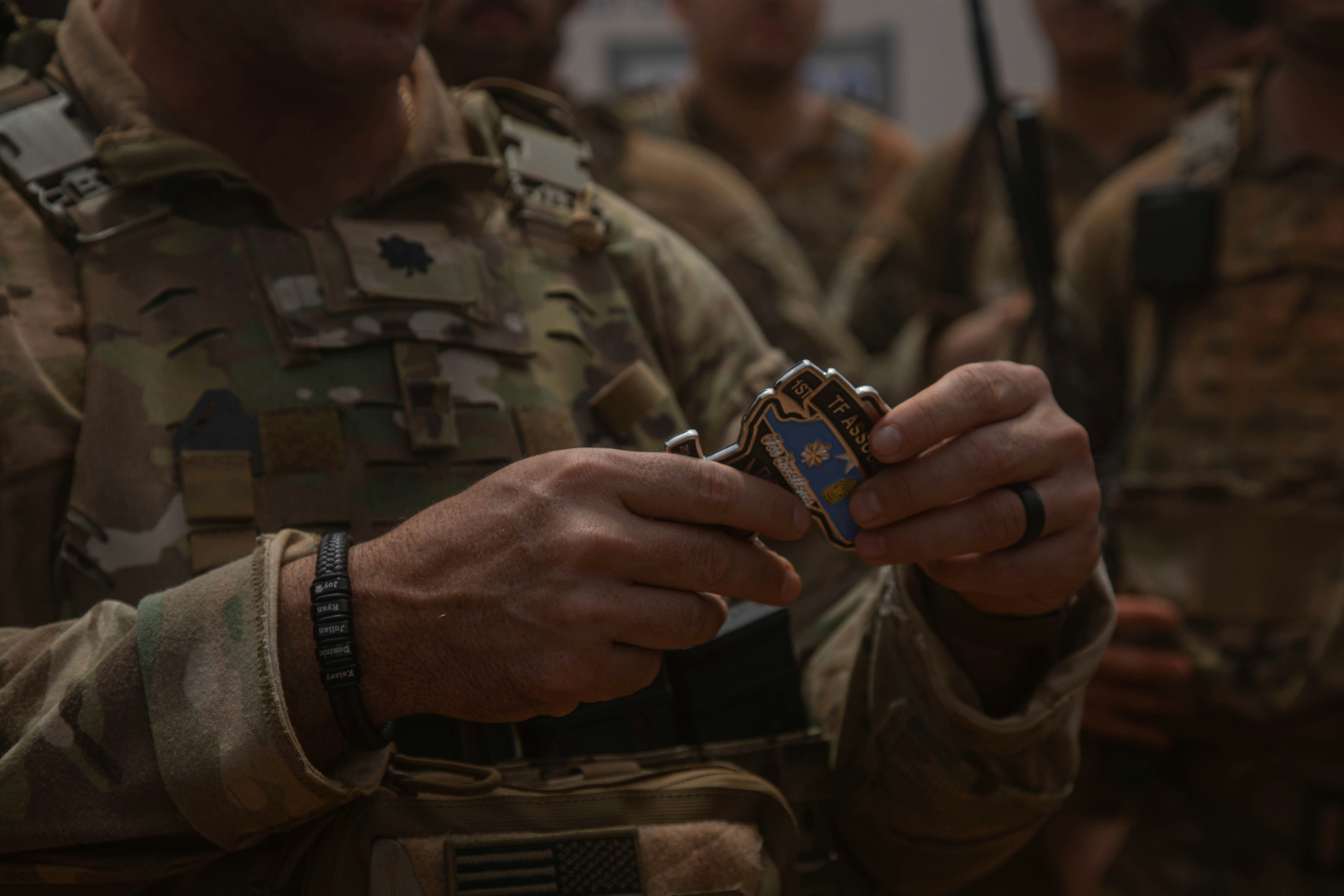 A man in military uniform smiling at a young girl wearing a camouflage cap.