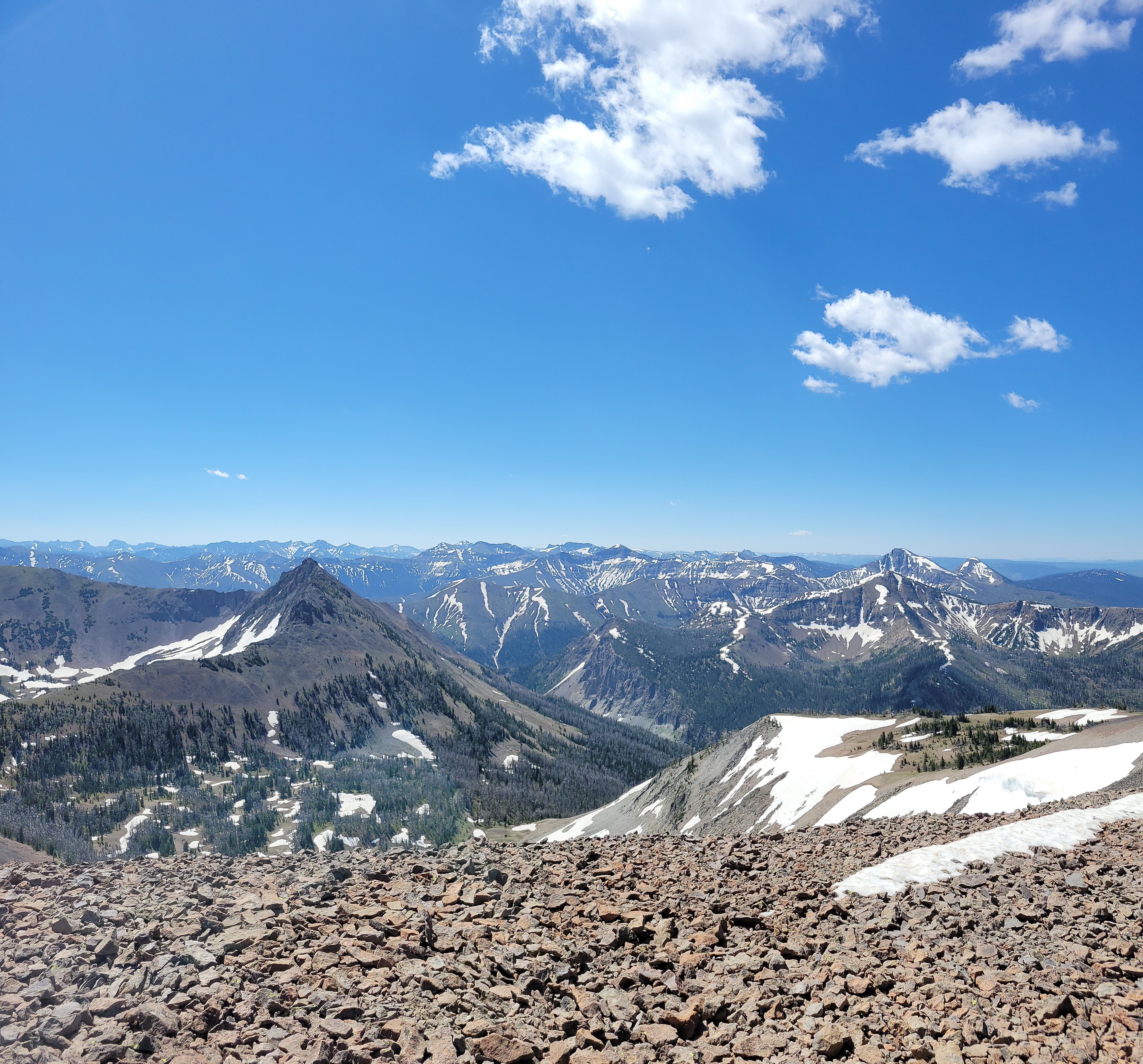 A view from a vista in Yellowstone, overlooking a mountain range with a clear blue sky.