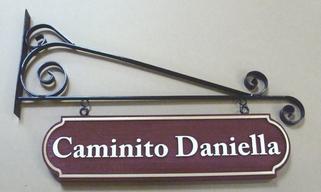 M1940 - Sandblasted Faux Wood Street Name Sign "Caminito Daniella"  hung from a Wrought Iron Scroll Bracket