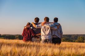 Four young people arm in arm in field