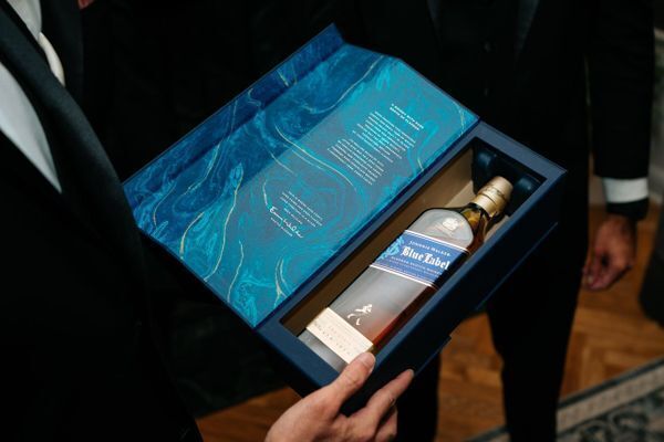 Man presenting a Johnnie Walker Blue Label bottle in a marbled blue gift box with gold script, one of the best unboxing experiences in luxury spirits.