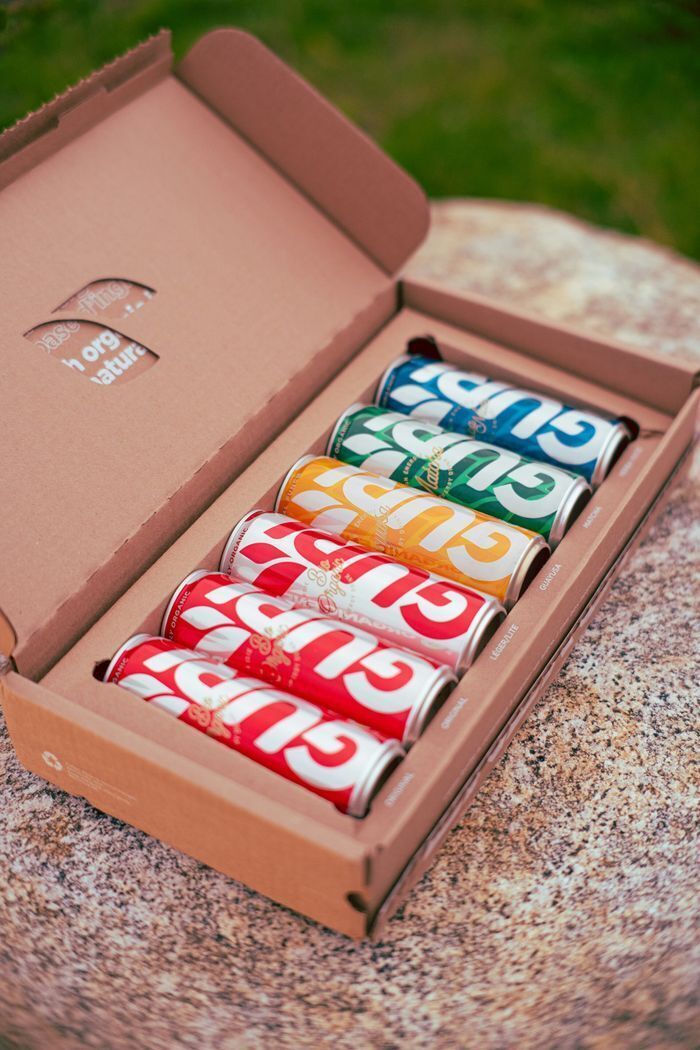 Corrugated e-commerce packaging carton utilizing a custom die-cut insert to securely ship beverage cans without plastic void fill