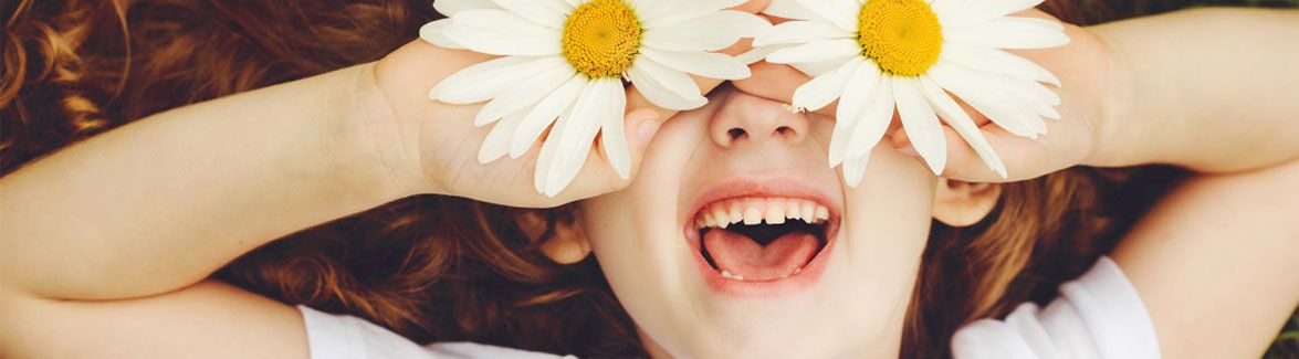 Girl holds flowers over eyes - CASA for Children