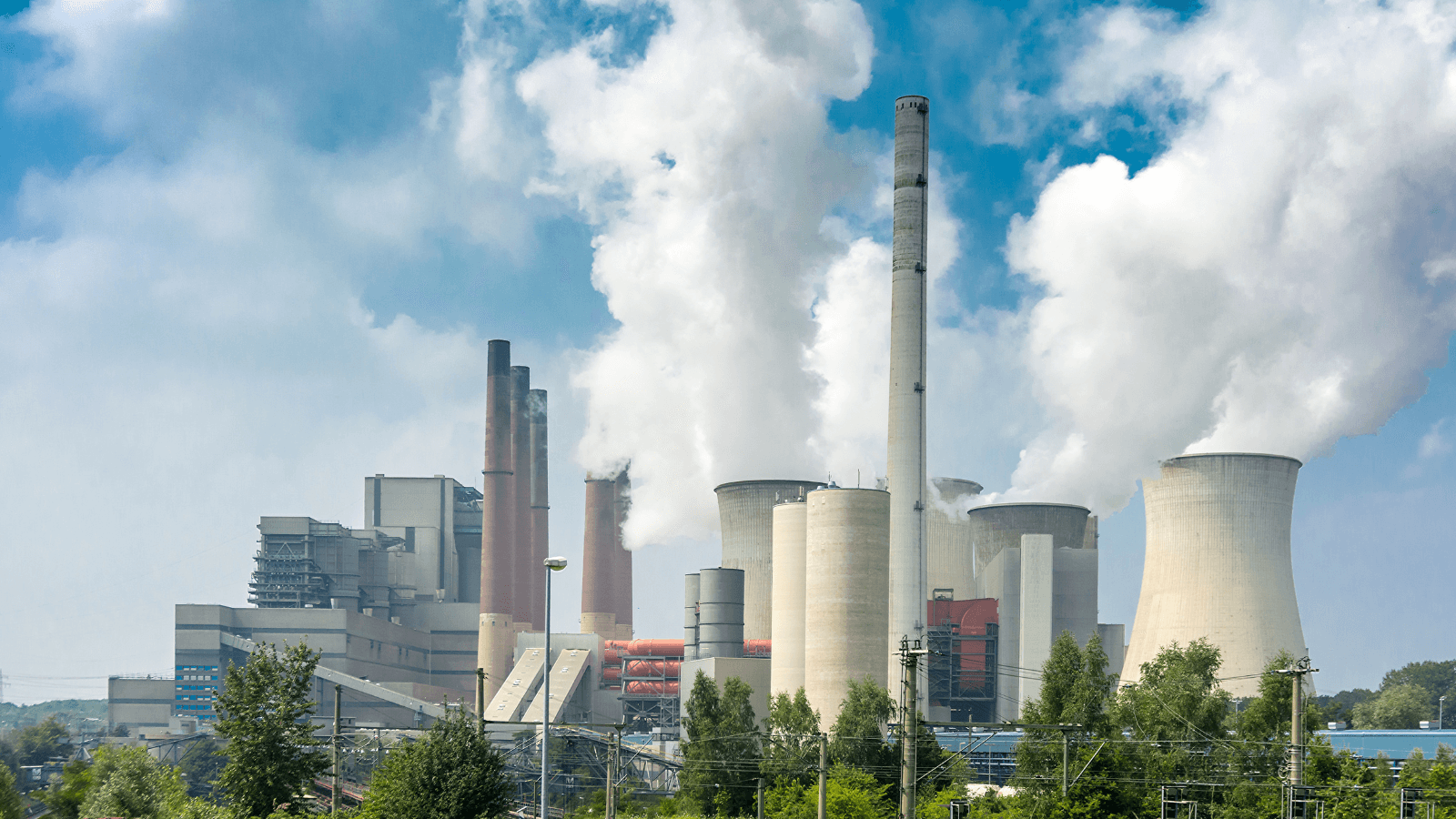 view of factory emitting greenhouse gases into a blue sky