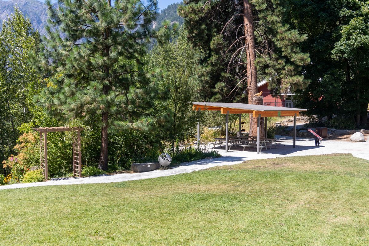 A view further away of the Outdoor Classroom, a covered outdoor structure next to a garden and the River Haus Lawn.