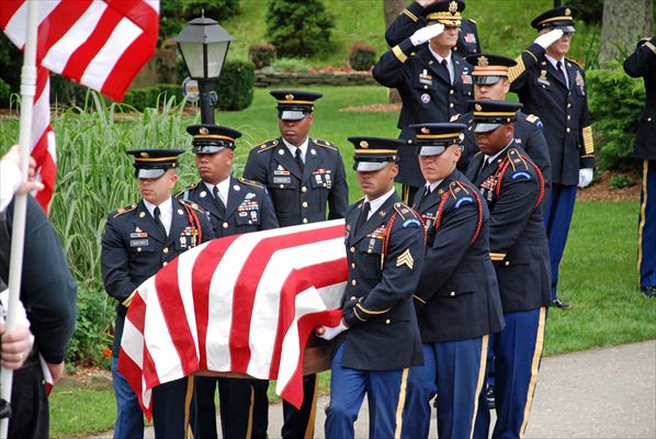 A military honor guard carries the flag draped casket of a fallen soldier