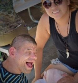 (Lower left corner) Native American man supported by PSRS with eyes closeda and mouth open wide and smiling. (Left) PSRS staff woman smiling at camera