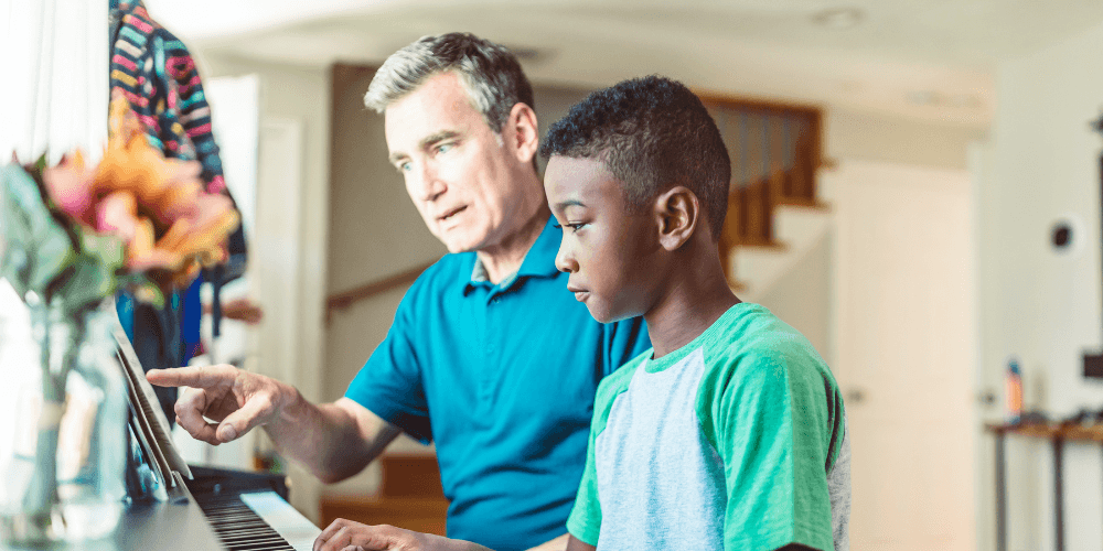 Man teaching boy piano