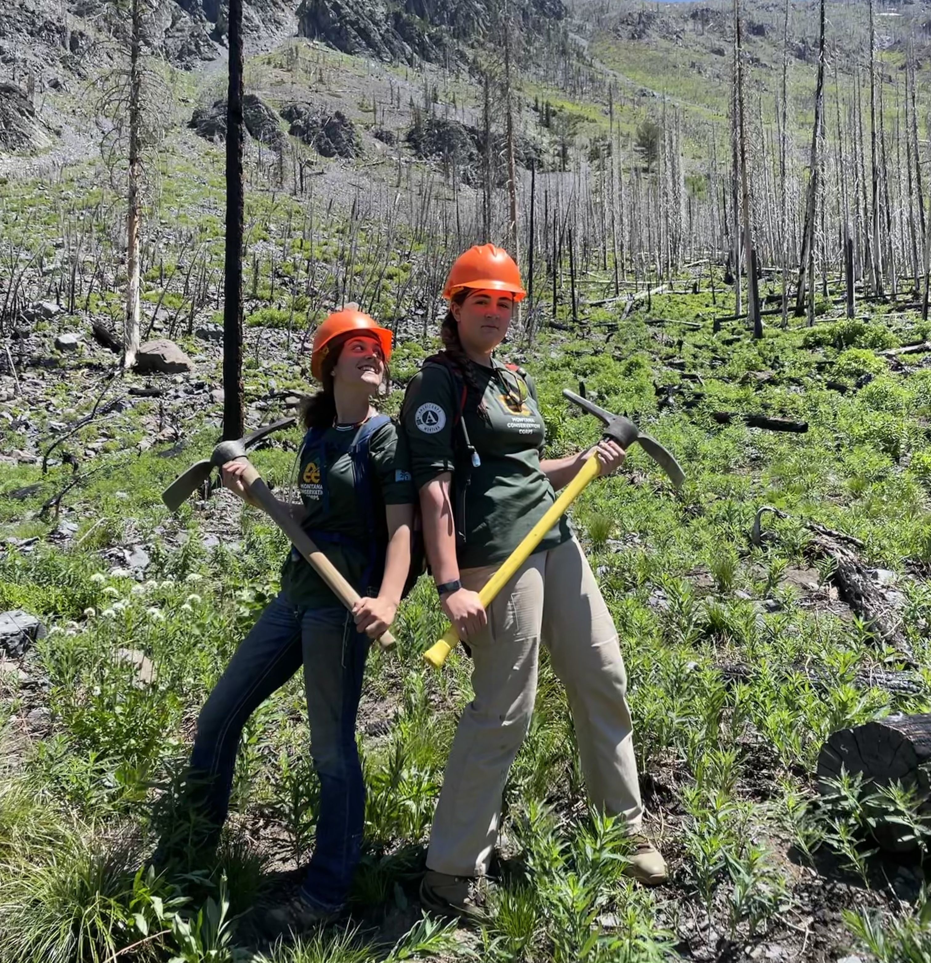 Two youth members wearing helmets stand back to back